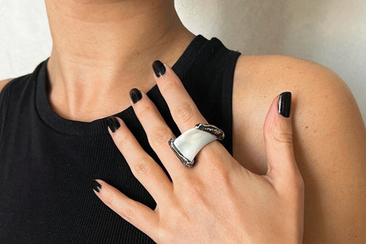 Close-up of a hand wearing a white mother of pearl ring with sterling silver