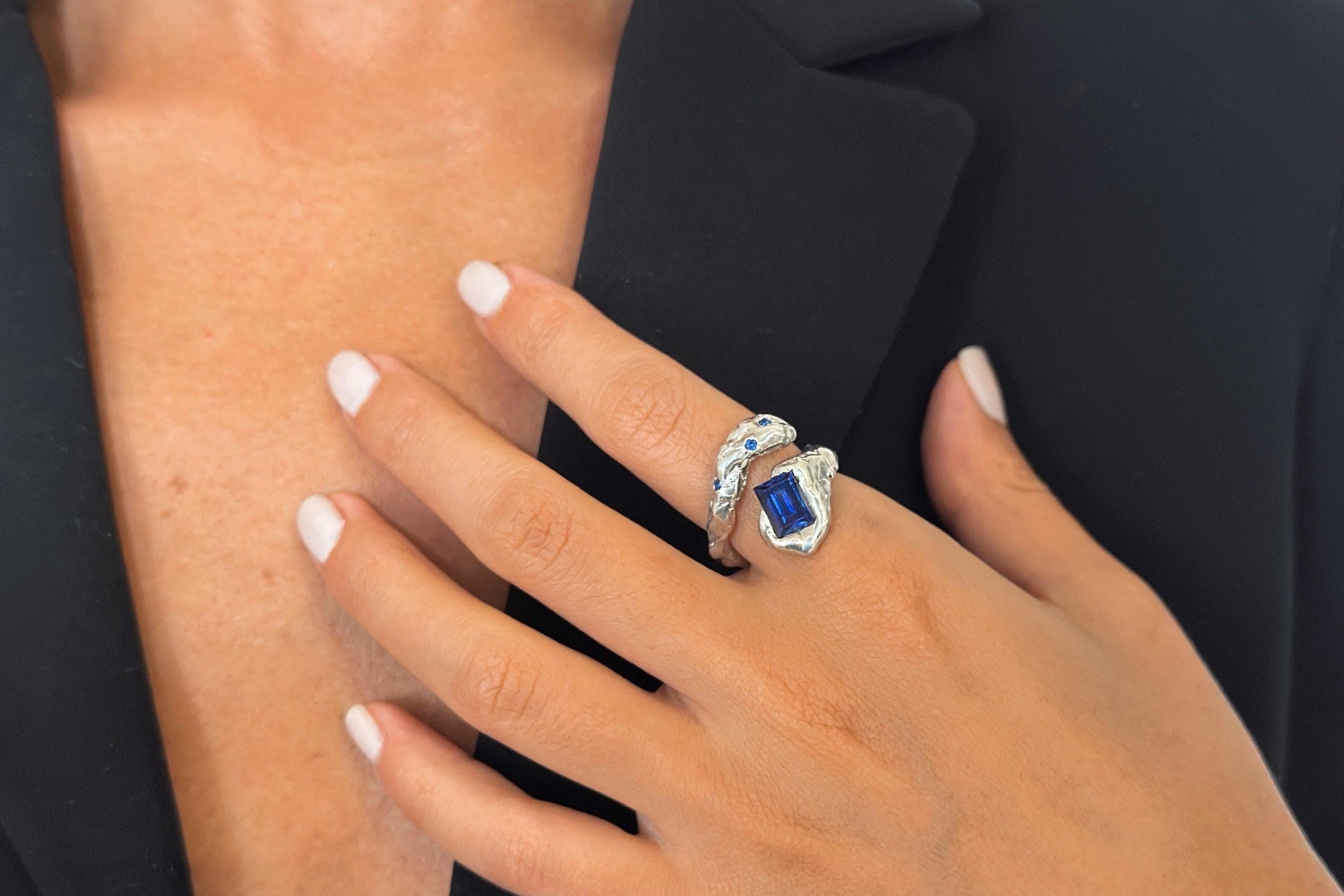 Hand wearing a ring with a blue zircon gemstone.